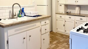 A kitchen with white cabinets, a sink, a stove, and a refrigerator.