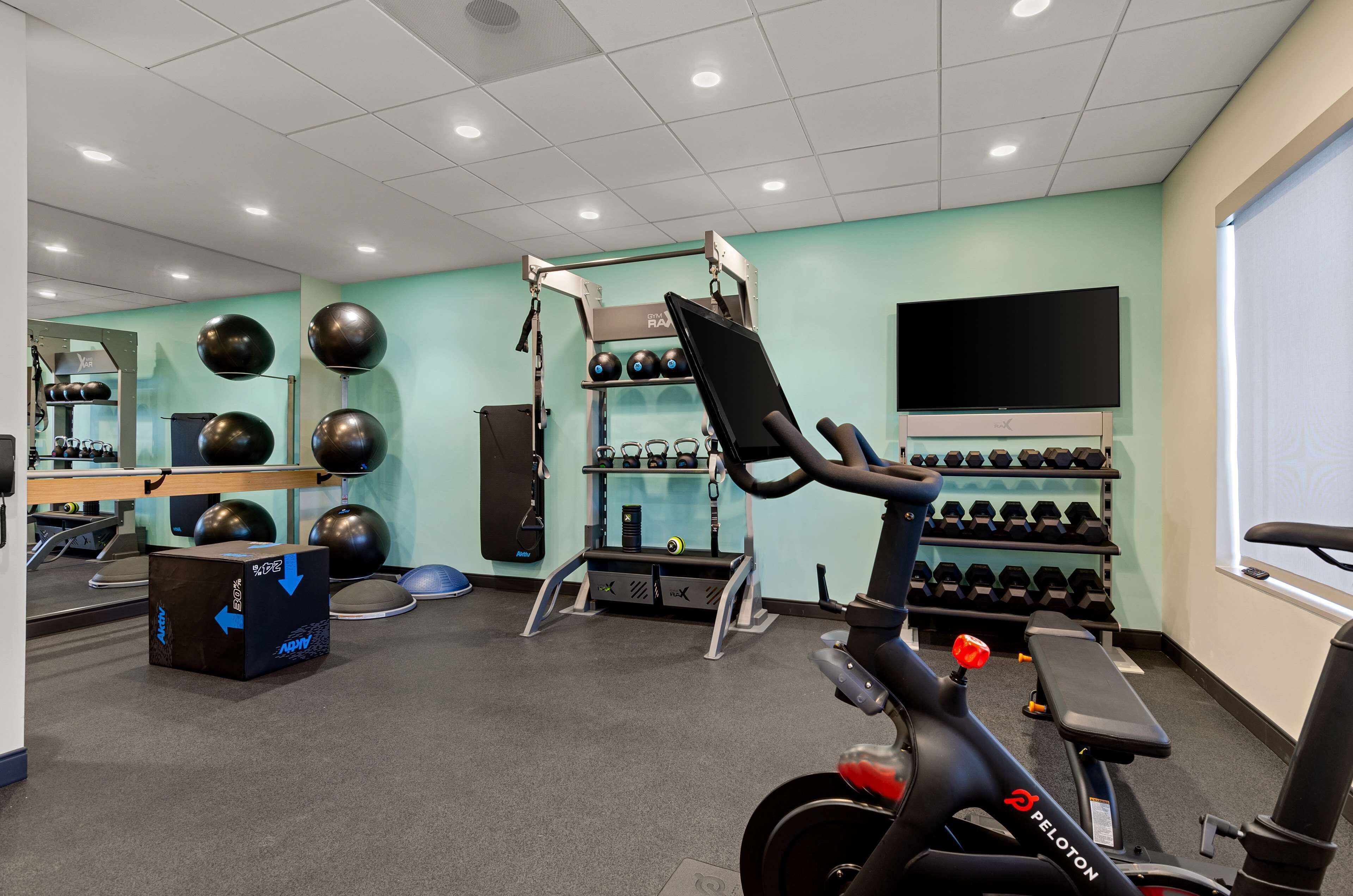 A gym with exercise equipment, a stationary bike, and a TV screen.