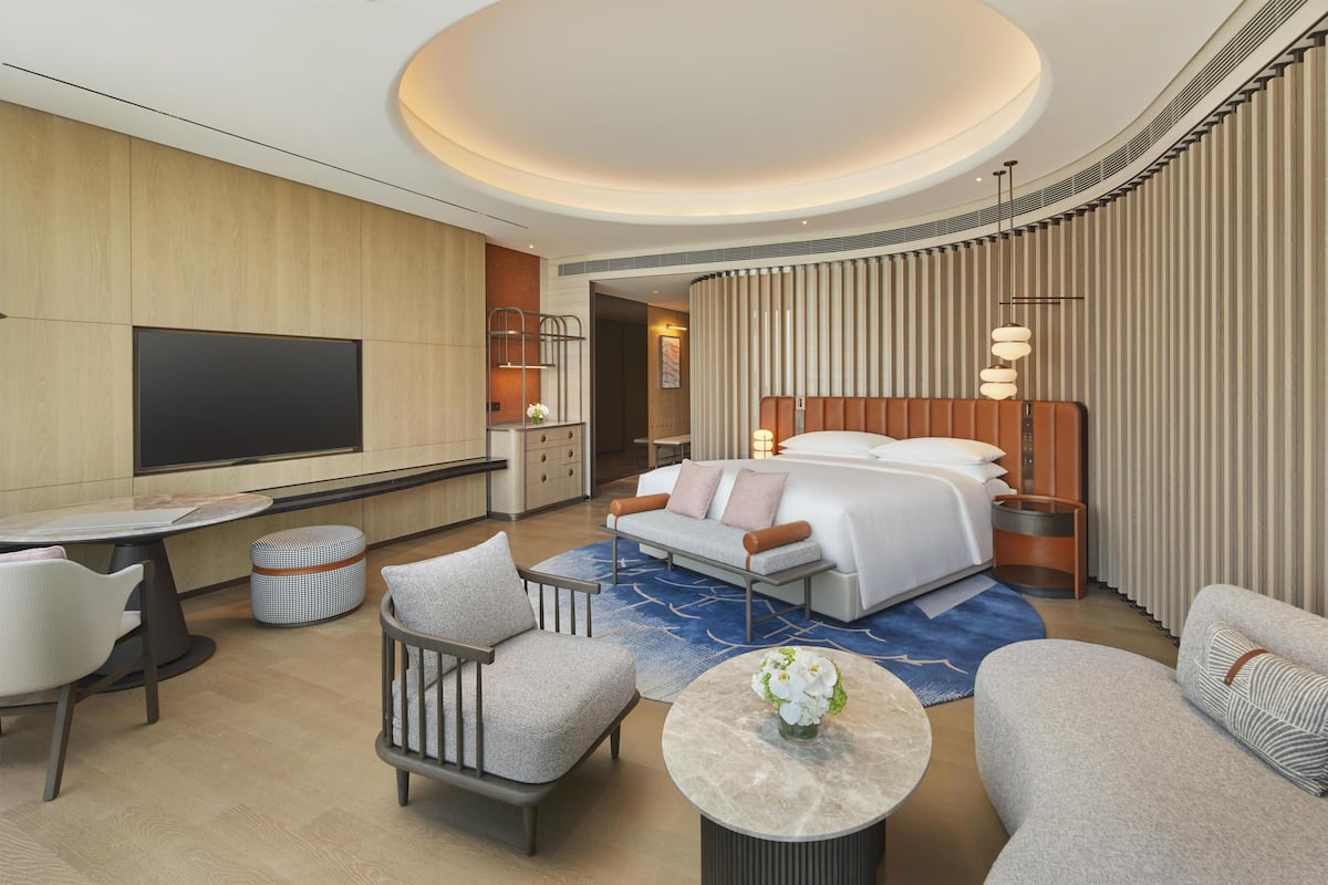 Ein modernes Hotelzimmer mit einem großen Bett, einem Flachbildfernseher, einem Esstisch und einer Sitzecke mit Couchtisch.