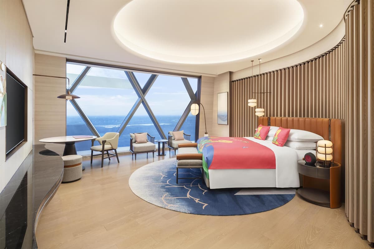 Ein modernes Hotelzimmer mit einem großen Bett, einem runden Tisch, einer Couch und einem Fernseher.