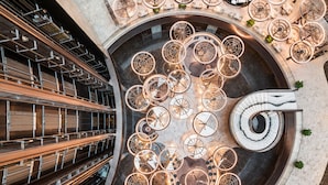 Een moderne atriumruimte met een centrale spiraaltrap, diverse zitgedeeltes en een grote, open ruimte met een cirkelvormig ontwerp.