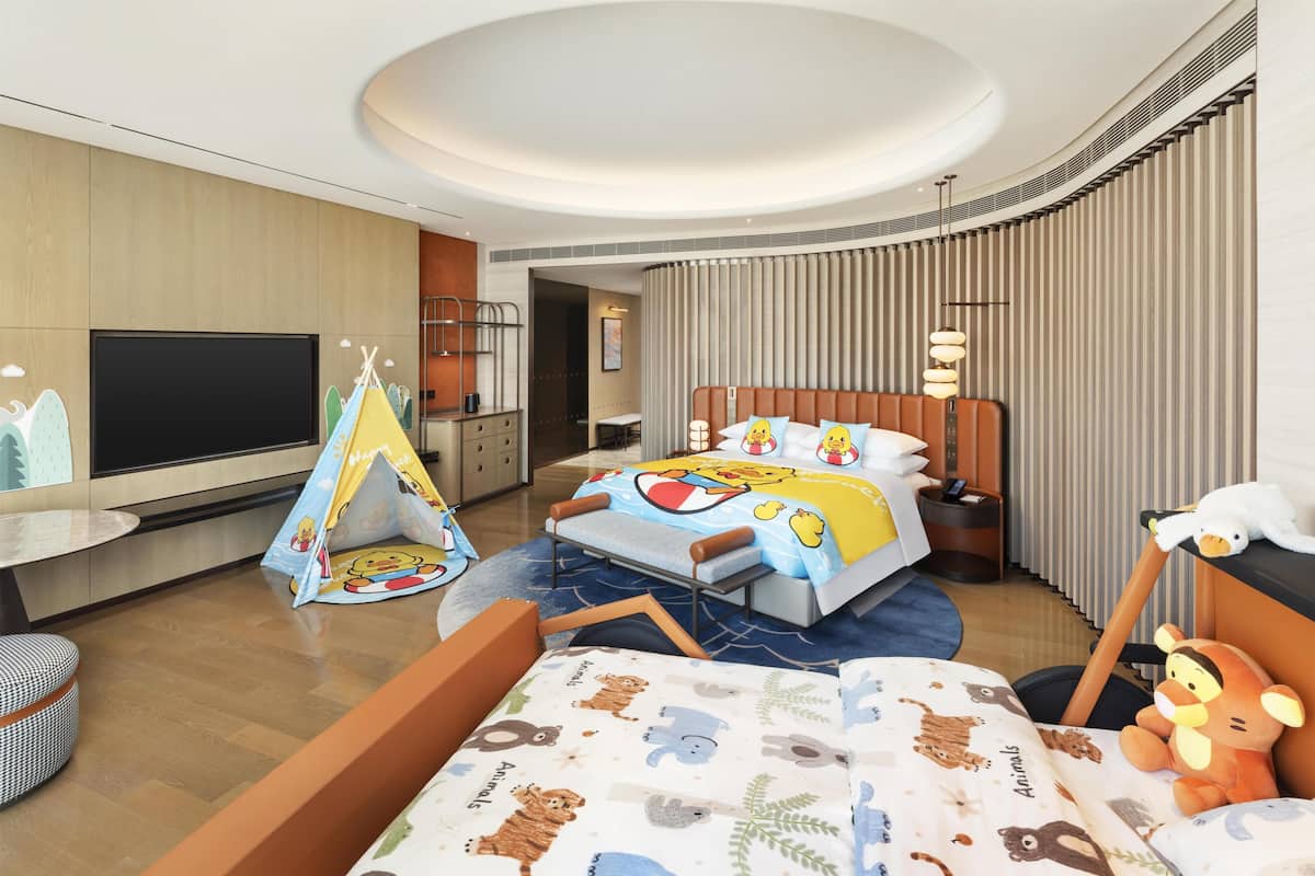 Ein Hotelzimmer mit Bett, Fernseher, Zelt und Stofftier.