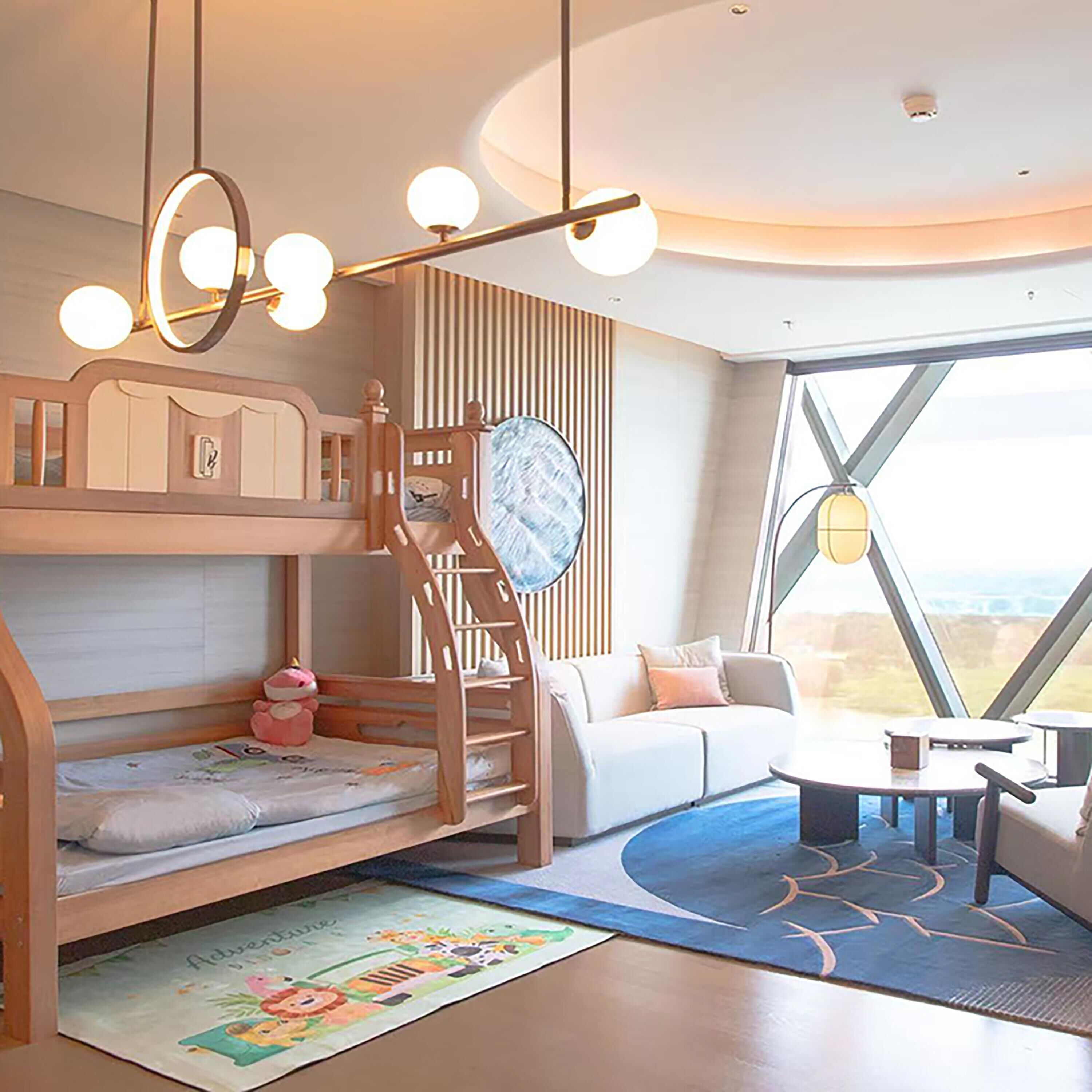 Een moderne kamer met een stapelbed, een slaapbank, een eettafel en een groot raam met uitzicht.