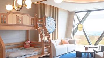 A modern room with a bunk bed, a sofa, a dining table, and a large window offering a view.