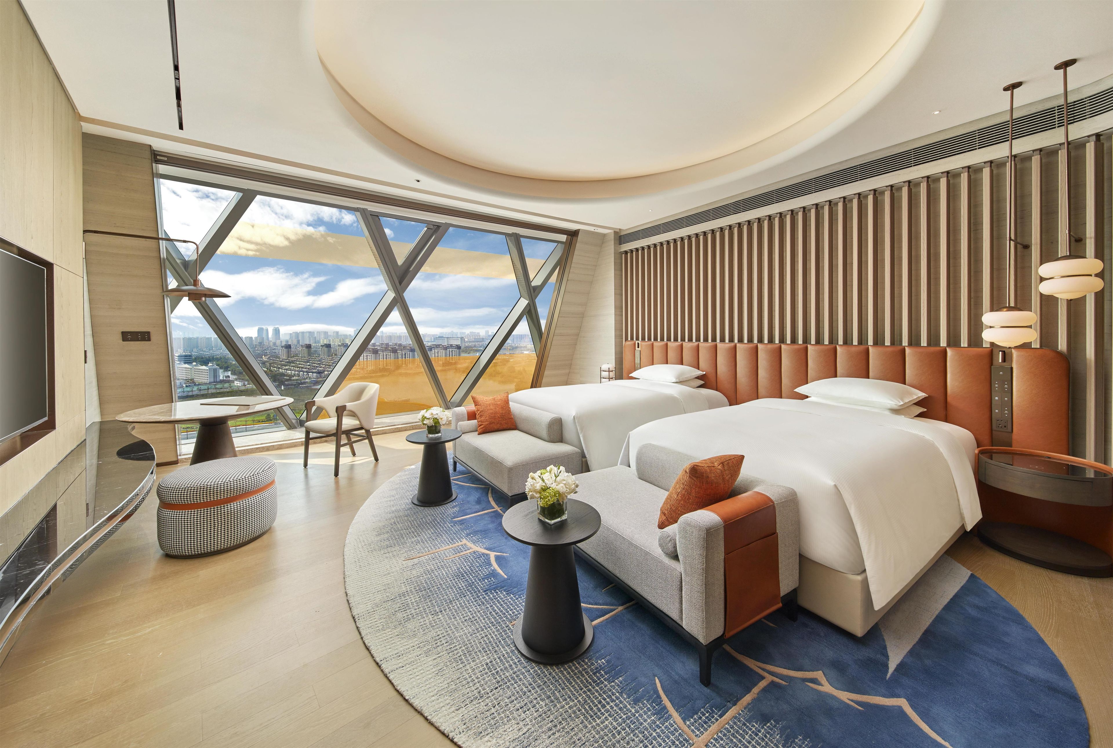 Habitació d'hotel moderna amb una finestra gran, un llit, zona de seients i una televisió.