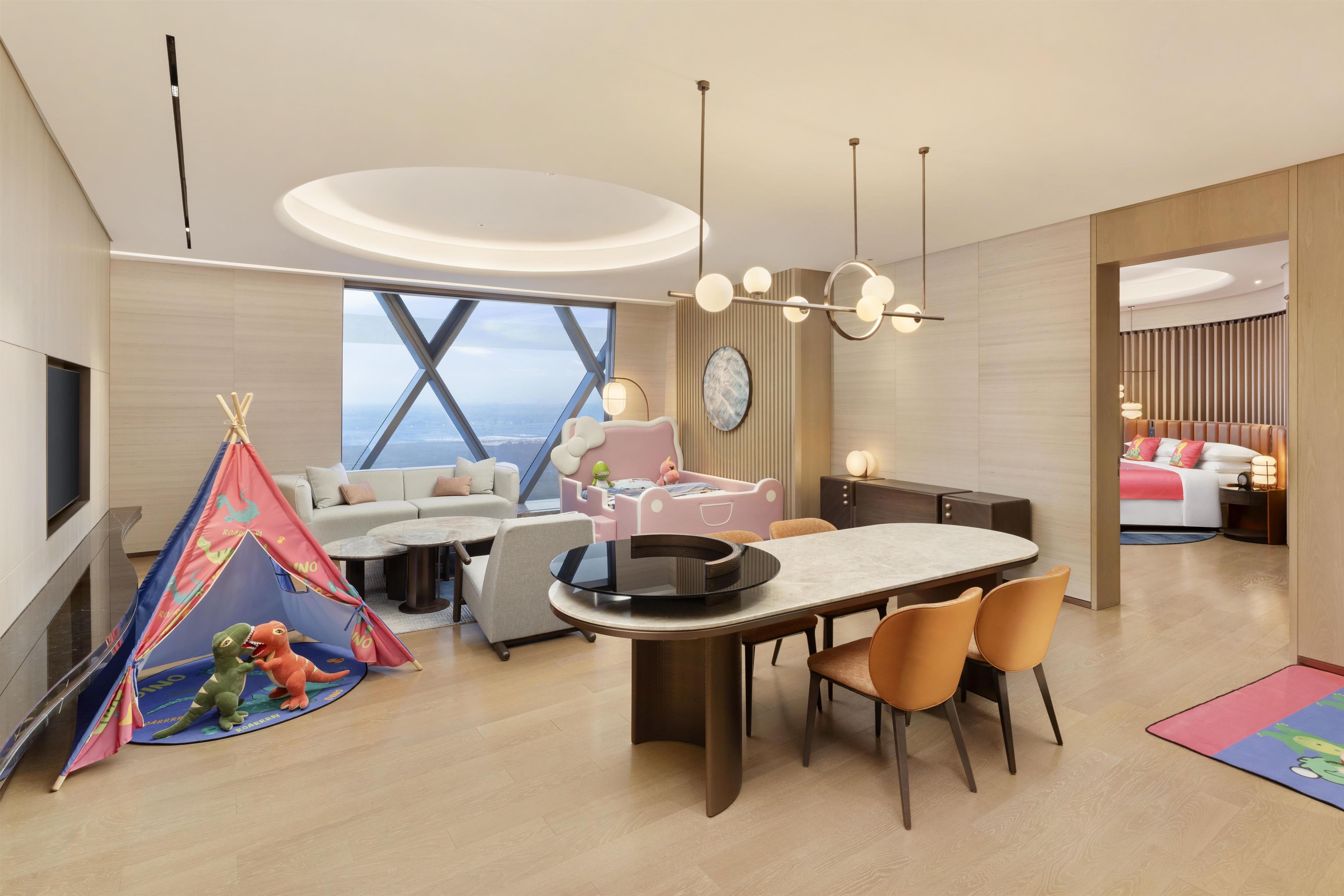 Habitación de hotel moderna con comedor, una tienda de juegos y un ventanal con vistas.