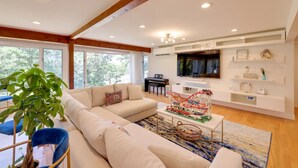 Una sala de estar moderna con un sofá modular, una mesa de centro con un tren modelo y un televisor montado en la pared.