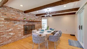 Un comedor con pared de ladrillo, vigas de madera y una mesa redonda con sillas.