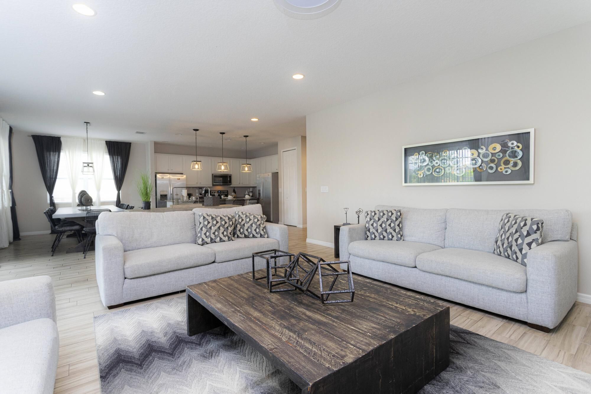 A modern living room with two grey sofas, a wooden coffee table, and a contemporary abstract painting.