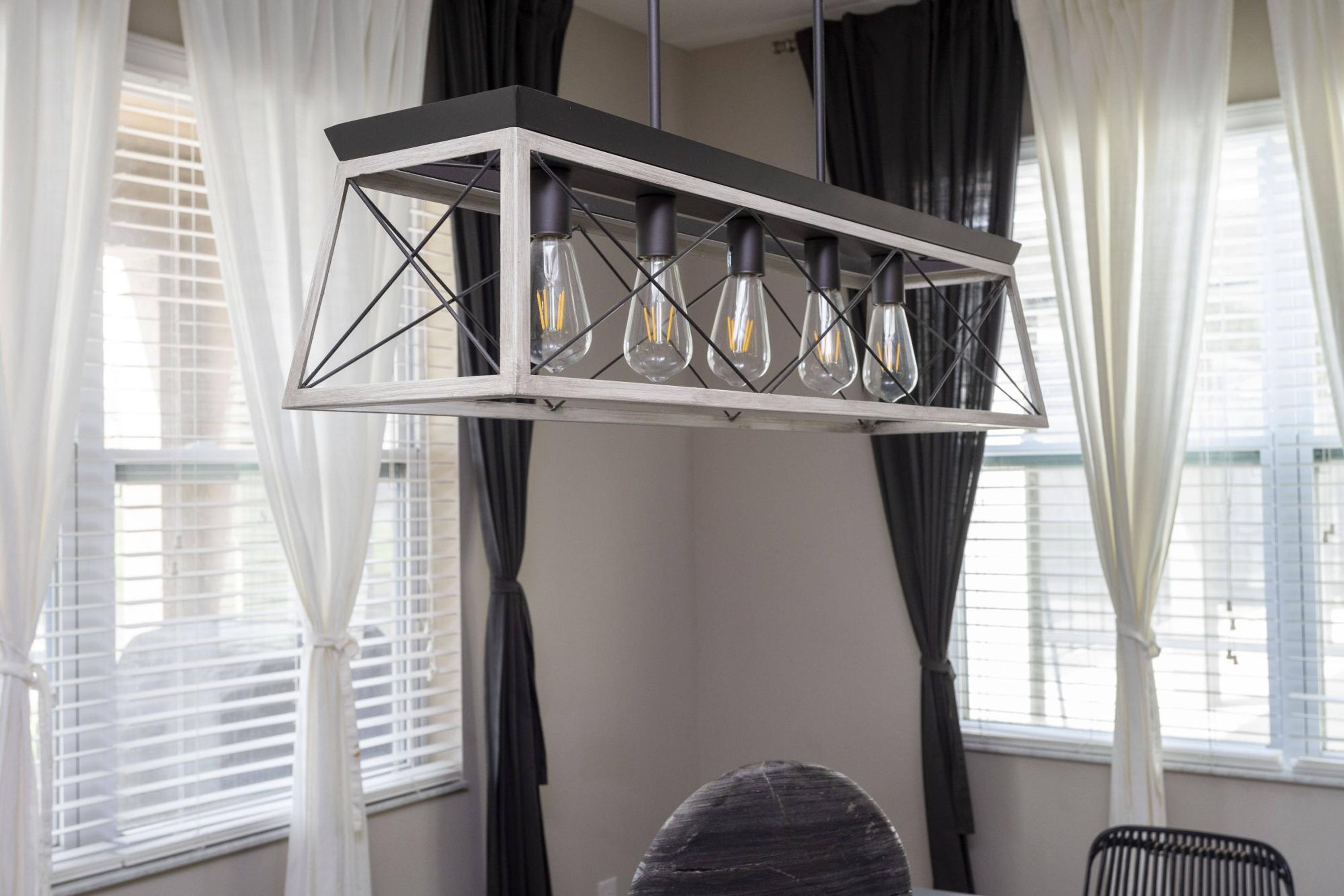 A modern chandelier with six light bulbs in a rectangular metal frame.