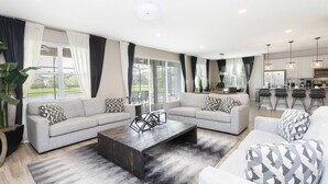 A modern living room with two sofas, a coffee table, and a kitchen in the background. - Amazing Dream Family Sleep21 Privatepool Veranda (Kissimmee)