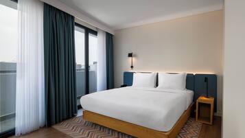 Une chambre d’hôtel moderne avec un grand lit, une vue sur la ville et une petite table de chevet.
