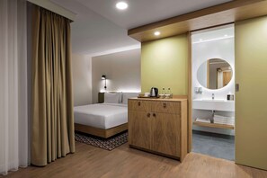 A hotel room with a bed, a wooden wardrobe, a bedside table with a lamp, a mirror, and a bathroom with a sink and mirror. - Hampton By Hilton Istanbul Sirkeci (Istanbul)