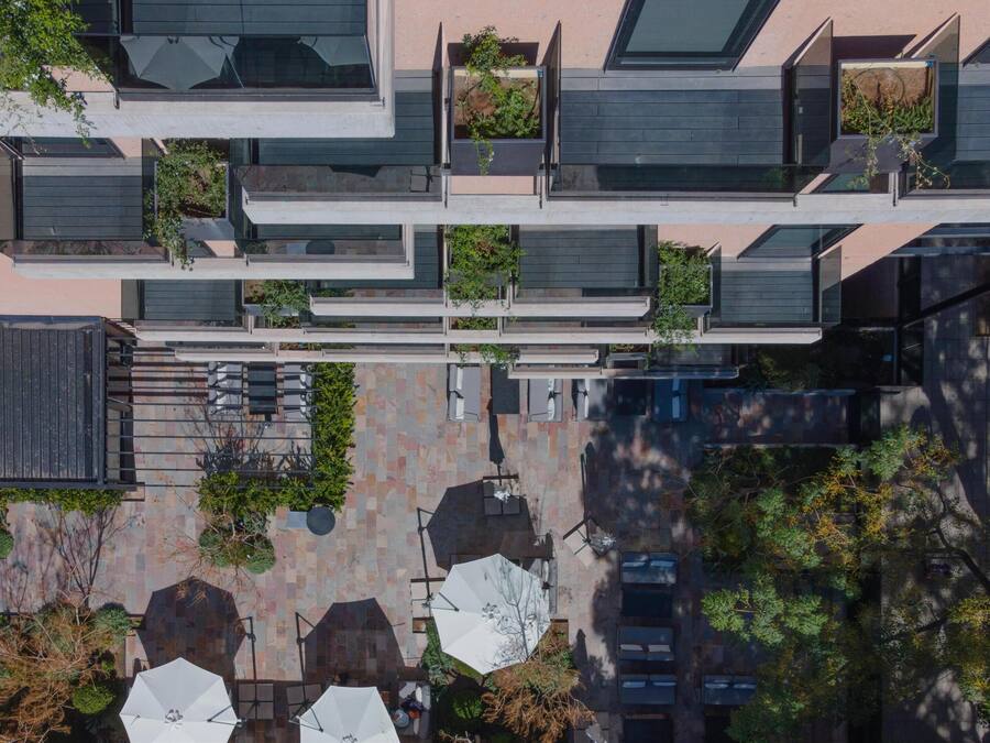 Un edificio moderno con varios balcones, zonas de estar al aire libre y una mezcla de vegetación.