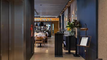 A hotel corridor with a dining area, a reception desk, and a reception area with a menu stand.