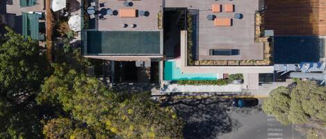 An aerial view of a modern building with a rooftop patio area featuring outdoor seating and umbrellas.