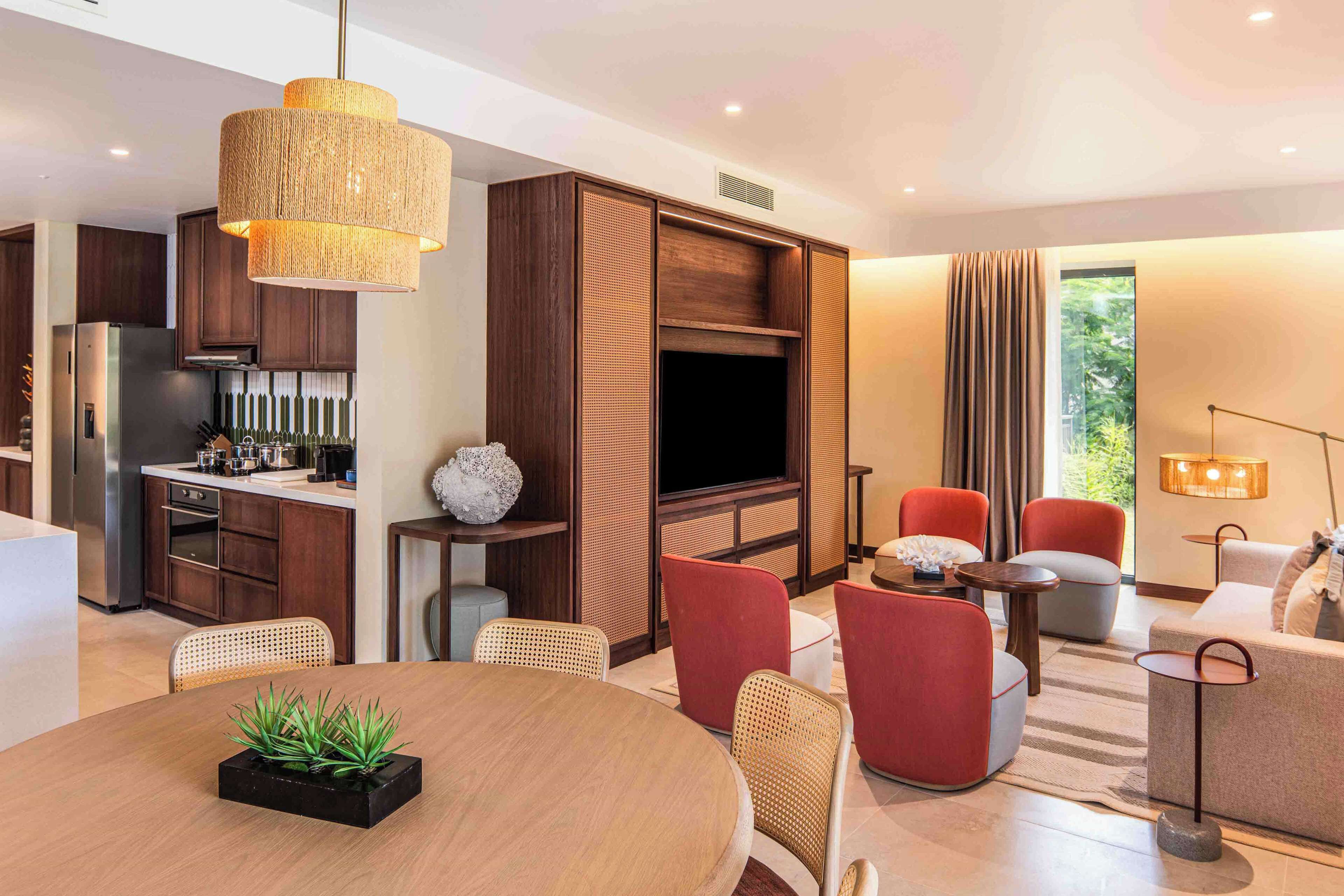 A modern living room with a dining area, a kitchen, and a large TV.