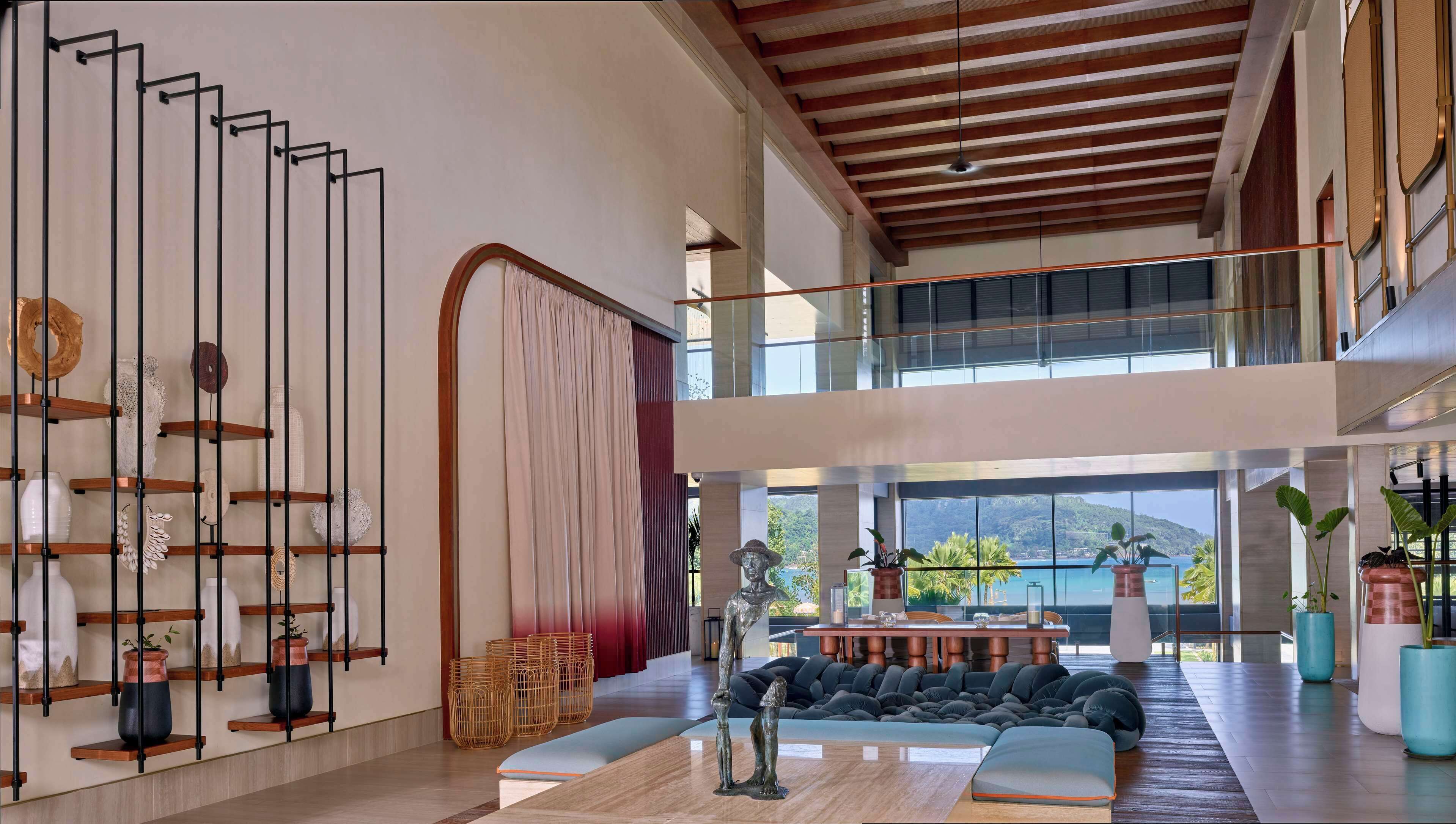 Un interior espacioso con techo alto, zona de estar central y vistas al exterior.