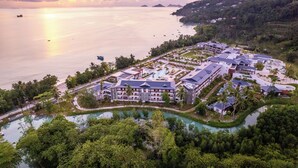 An aerial view of a resort with multiple buildings, a swimming pool, and a view of the ocean. - Canopy by Hilton Seychelles Resort (Mahé Island)