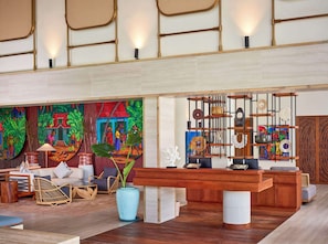 A spacious lobby with a large reception desk, comfortable seating, and a vibrant mural.