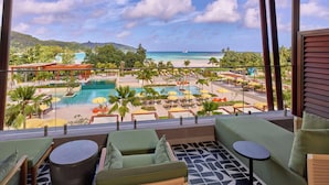 A balcony with a view of a pool, lounge chairs, and a tropical landscape. - Canopy by Hilton Seychelles Resort (Mahé Island)