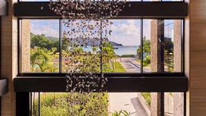 A modern interior with a large window overlooking a landscaped outdoor area. - Canopy by Hilton Seychelles Resort (Mahé Island)