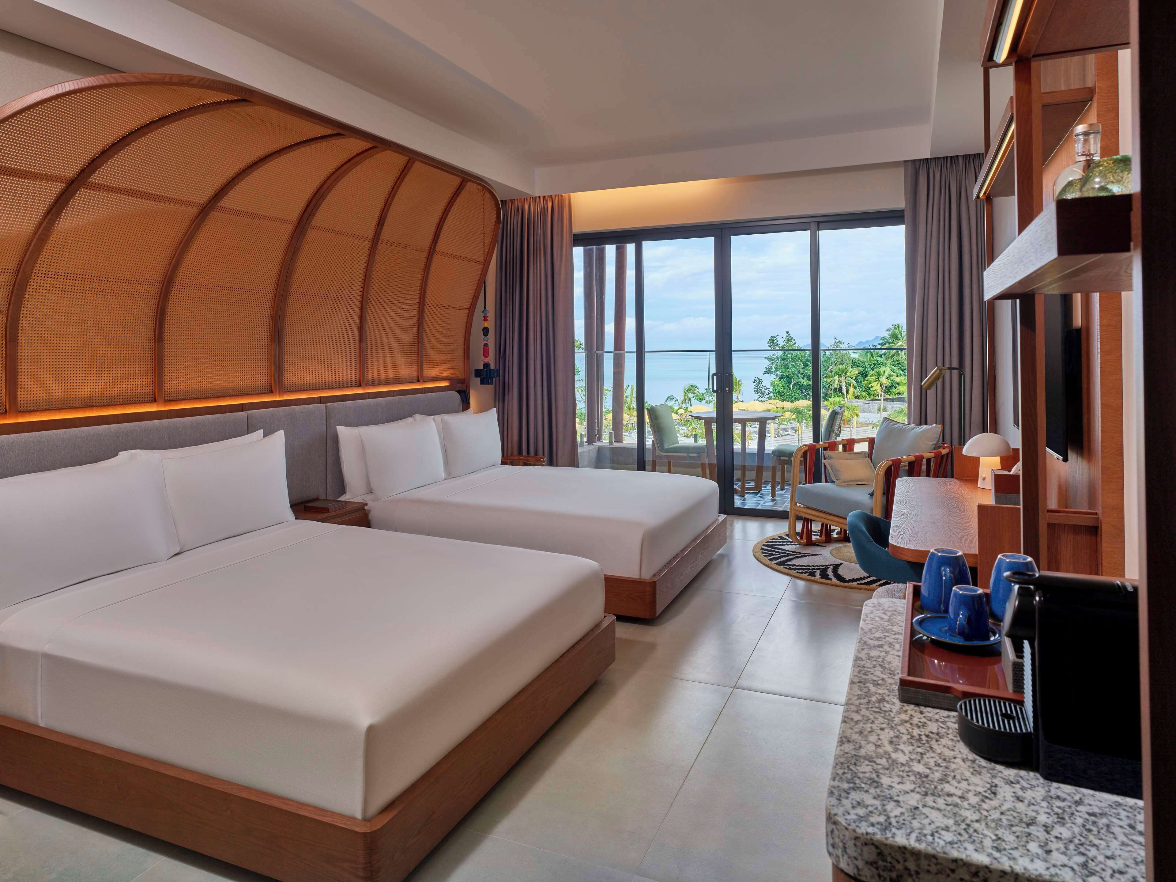 A hotel room with two beds, a balcony with a view, and a kitchenette.
