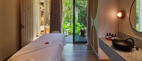 A bedroom with a bed, a bathroom with a sink, and a view of greenery outside.