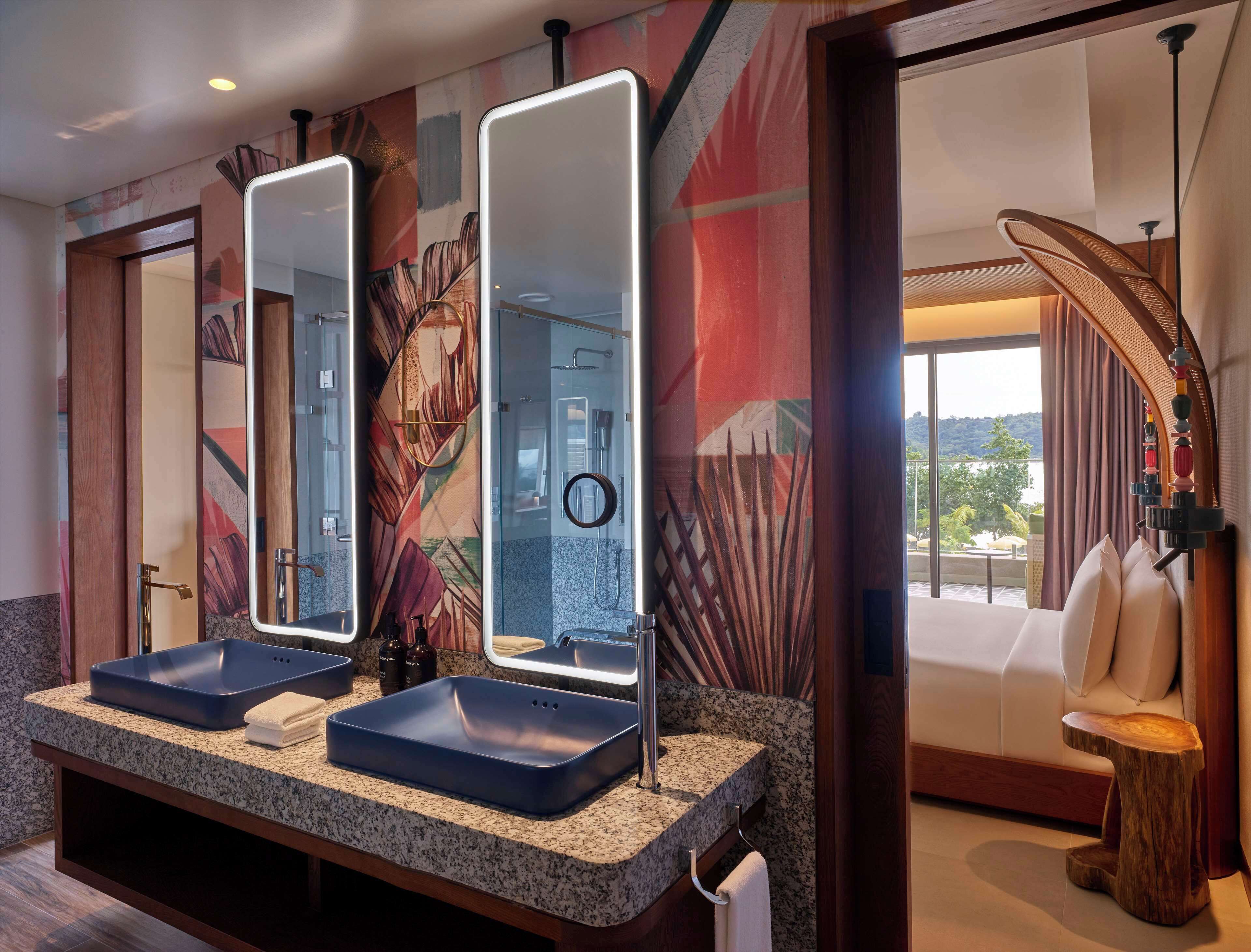 A bathroom with two sinks, a large mirror, and a view of a balcony.