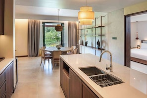 A modern kitchen with a central island, a dining area with chairs, and a large window with curtains.