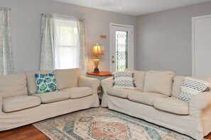 Cozy living room with two sofas, a patterned rug, and a wooden side table with a lamp.