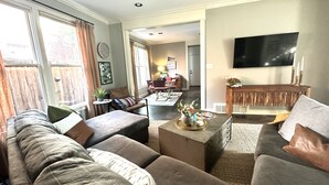 A living room with a sofa, coffee table, and a TV on the wall.