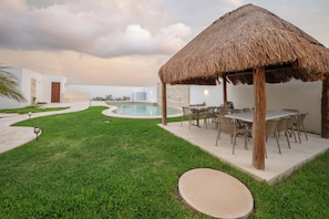 Relax in a serene outdoor setting with a pool, gazebo, and dining area.