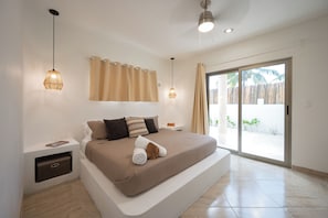 Relax in a serene bedroom with a large bed and sliding door to an outdoor area with a palm tree view.