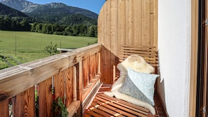 Un balcone in legno con vista su un prato verde e montagne.