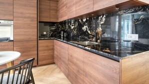 Una cocina moderna con armarios de madera, encimera de mármol negro y pileta de acero inoxidable.