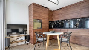 Una cocina moderna con armarios de madera, un salpicadero de mármol negro y una mesa de comedor redonda con sillas.
