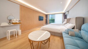 A modern hotel room with a large bed, a sofa, a small round table, and a TV mounted on the wall. - Donghae Badae Meomuleuda (Donghae)