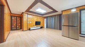 A spacious room with wooden walls and floors, a large refrigerator, a flat-screen TV, and a sliding door with a floral design. - Donghae Badae Meomuleuda (Donghae)