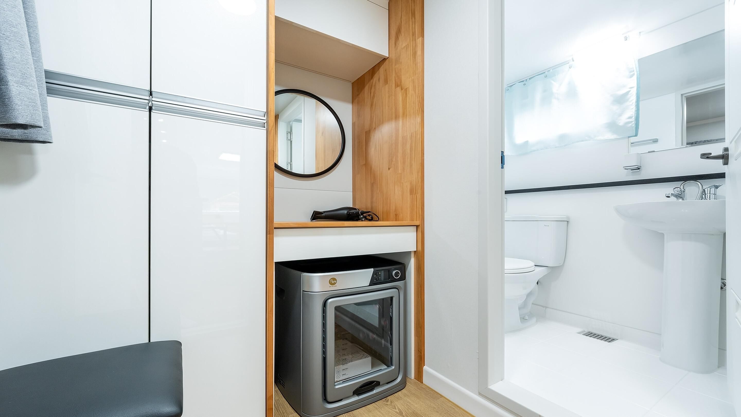 A compact, modern bathroom with a built-in oven, a mirror, and a toilet.