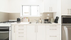 A modern kitchen with white cabinets, a stove, oven, and a microwave. - Garden View Cottage(2 Bedroom,2 Bathroom) (Kingston)