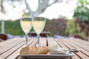 Two glasses of white wine on a wooden table with a plate of cheese and crackers. - 2 bedrm, 2 bathrm house w/patio includes car (Kingston)