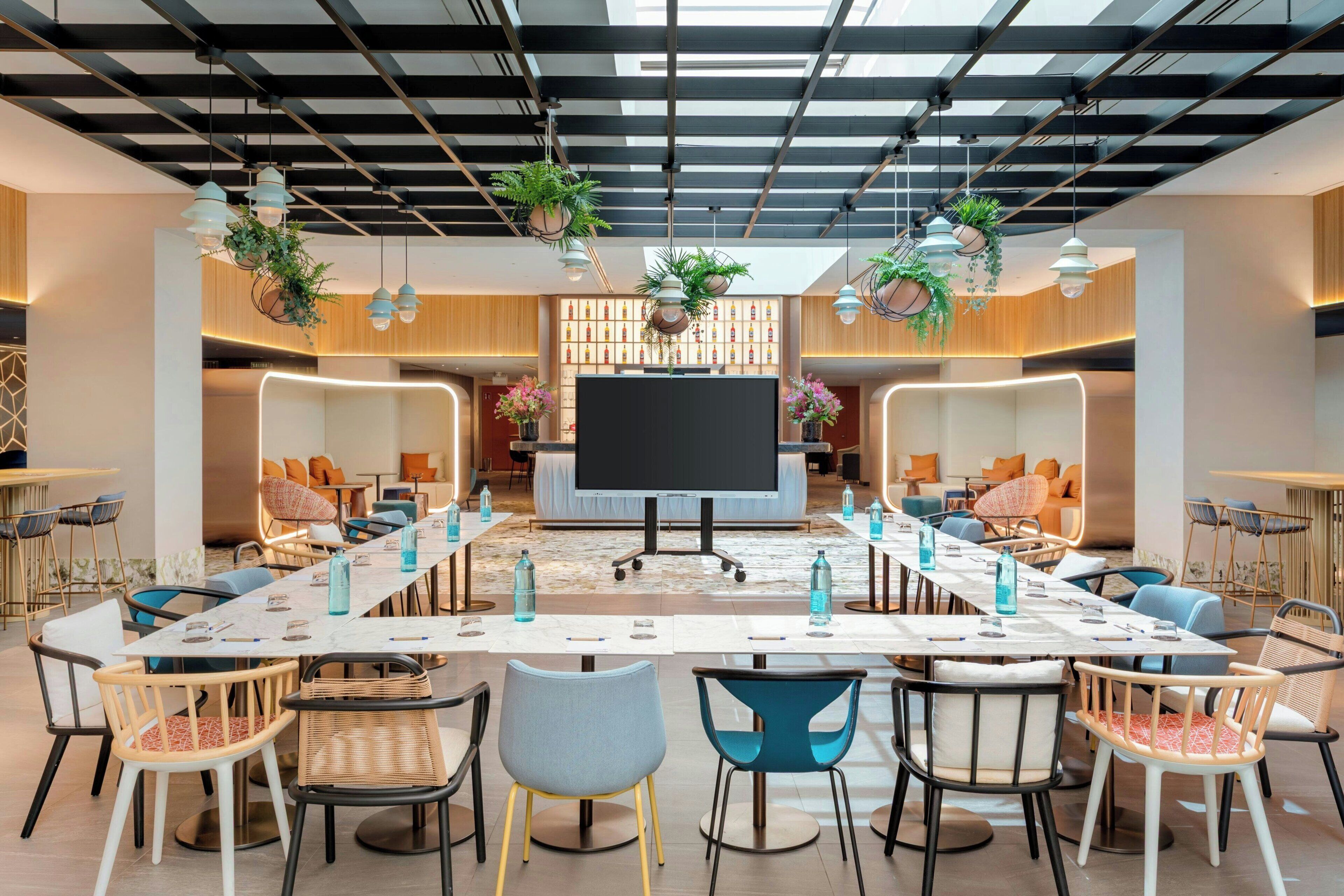 A modern conference room with a long table, chairs, and a large screen.