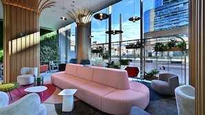 A modern lounge area with a large sofa, seating, and a view of the cityscape through large windows.