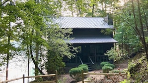 Eine Holzhütte mit Metalldach, umgeben von dichten Bäumen und einem Holzzaun.