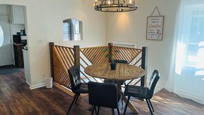 Een eetruimte met een ronde houten tafel, zwarte stoelen, een kroonluchter en een decoratief bord.
