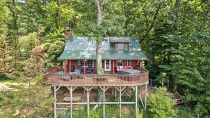 A cabin with a wooden deck, a covered porch, and a small window. - 4BD Rustic Log Cabin With Incredible Deck and View! (Gatlinburg)