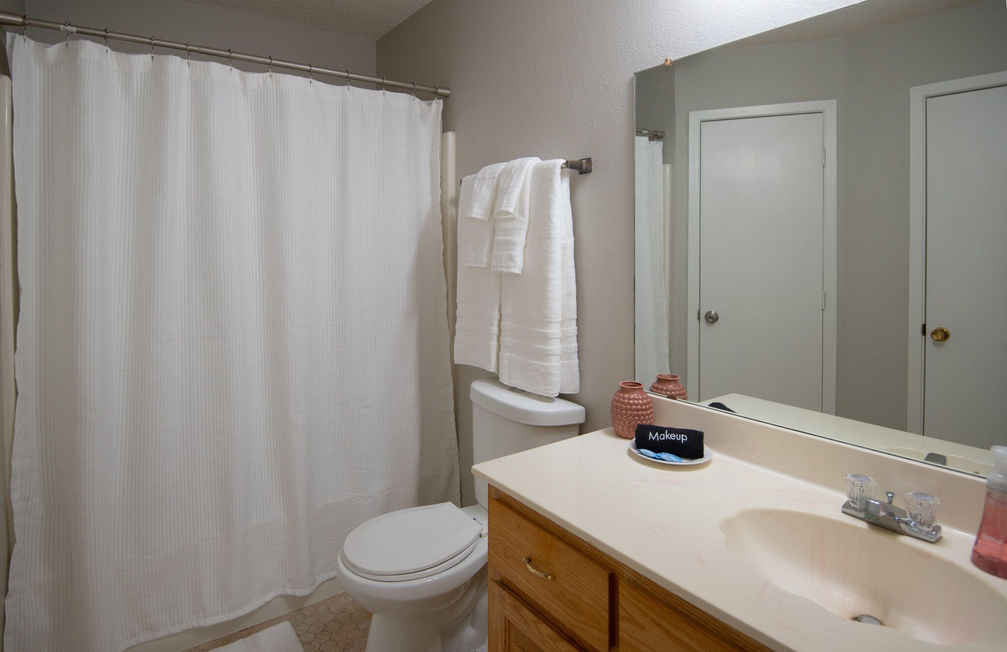 A bathroom with a toilet, a sink, a mirror, and a shower curtain.