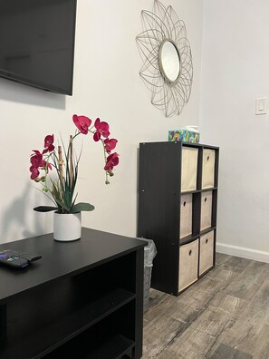 Relax in this serene living space with a black entertainment unit, a potted orchid, and a decorative metal wall piece.