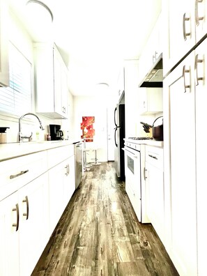 Enjoy cooking in this well-equipped kitchen with a refrigerator, oven, and sink, plus a coffee maker and bar stool.
